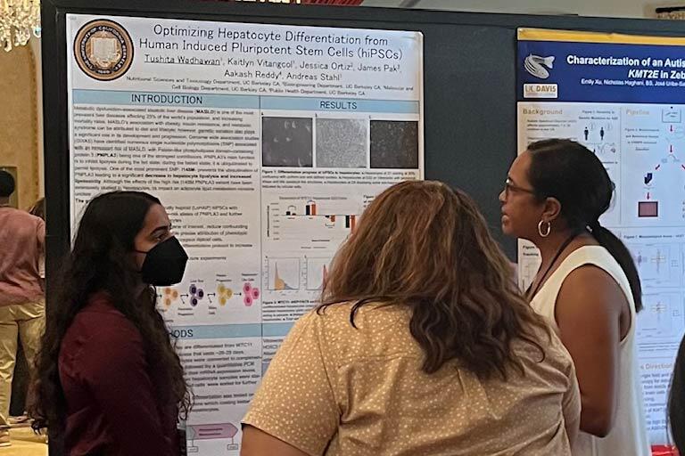 Tushita Wadhawan presenting her research poster to two other conference attendees